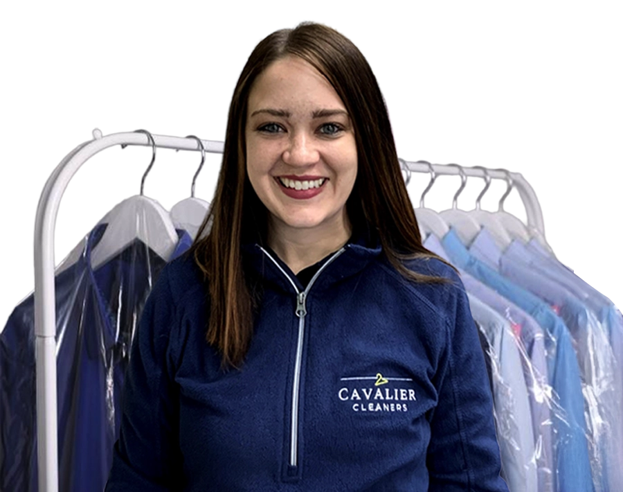 A woman in a "Cavalier Cleaners" uniform stands in front of a clothing rack with garments covered in plastic.